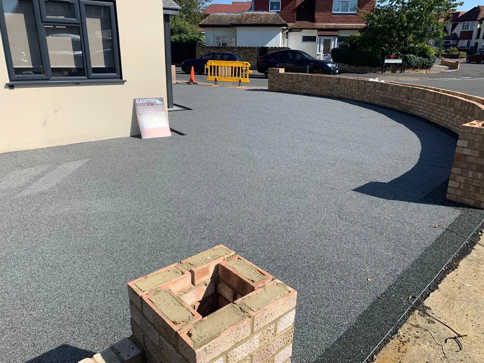 Finished charcoal resin-bound driveway with a new brick boundary wall in Worcester Park, Surrey